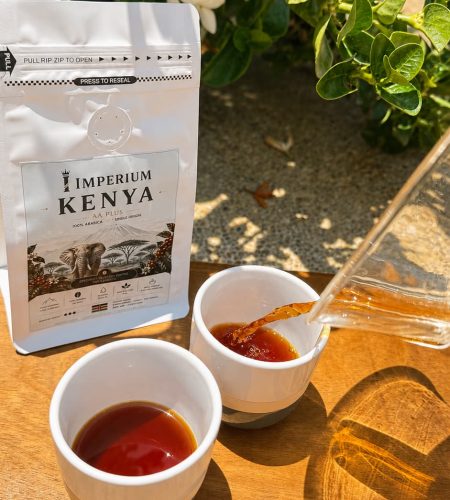 Freshly brewed Kenyan coffee being poured into cups outdoors in sunlight.